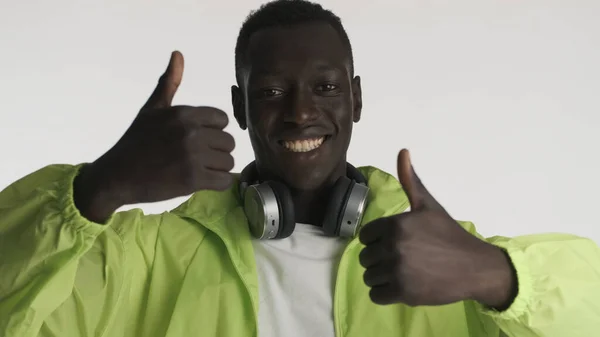 Atrakcyjny Przyjazny Afroamerykanin Jasnej Kurtce Słuchawkami Trzymającymi Kciuki Górze Wyglądający — Zdjęcie stockowe