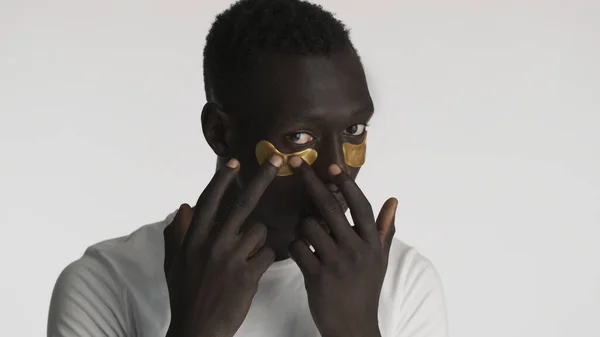Atraente Afro Americano Aplicando Manchas Olho Ouro Isolado Fundo Branco — Fotografia de Stock