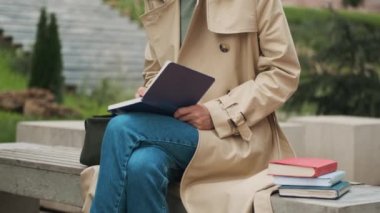 Üniversite için ödev yapan güzel bir öğrencinin resmini çekiyorum. Şehir parkında kitaplarla bankta oturuyor. Dışarıda okuyan genç bir kadın.