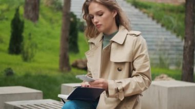 Parkta bankta ders çalışırken telefonda konuşan güzel bir öğrenci kız. Eğitim kavramı