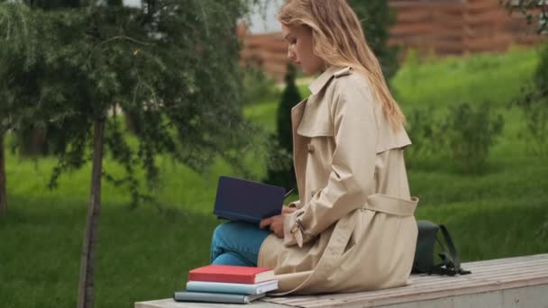 在公园的长椅上看书的金发女学生的侧视图 教育概念 — 图库视频影像