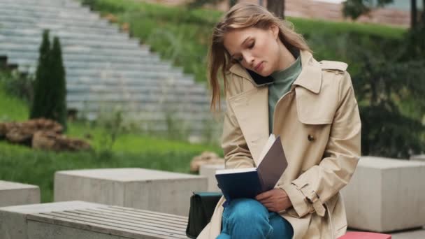 Attraktive Studentin Trenchcoat Macht Sich Notizen Notizblock Gespräch Mit Freund — Stockvideo