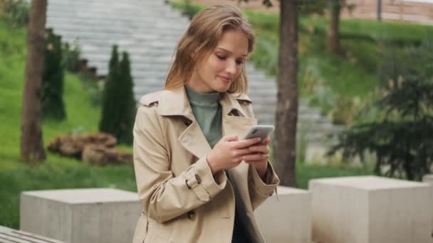 Beautiful Smiling Blond Student Girl Looking Happy Texting Friend Smartphone — Stock Video