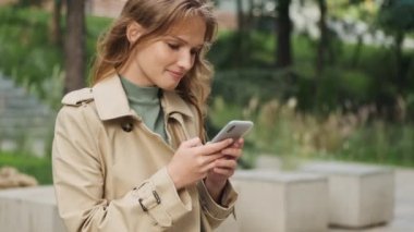 Şehir parkında arkadaşlarıyla mesajlaşırken farklı duygular gösteren güzel bir öğrenci kız.