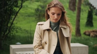 Trençkot giymiş çekici sarışın kız. Üniversiteyle ilgili dedikodu yapıyor. En iyi arkadaşı telefonda konuşuyor.