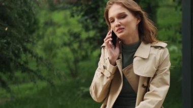 Çekici öğrenci kız, akıllı telefondan arkadaşıyla konuşuyor. Dersten sonra parkta bankta dinleniyor.