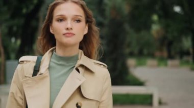 Şehir parkında üniversiteye giderken kendine güvenen çekici ve şık bir kızın fotoğrafını çekiyorum.