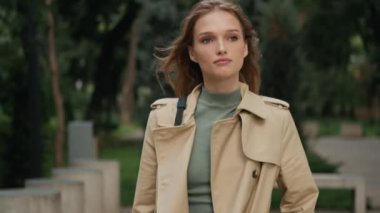 Trençkot giymiş çekici kız üniversiteden sonra sıcak şehir parkında evine gidiyor.