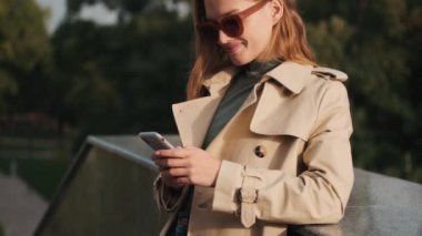 Güneş gözlüklü ve trençkotlu çekici bir kız sokakta dikilip en iyi arkadaşıyla akıllı telefondan mesajlaşıyor. Hep görüşüyoruz.