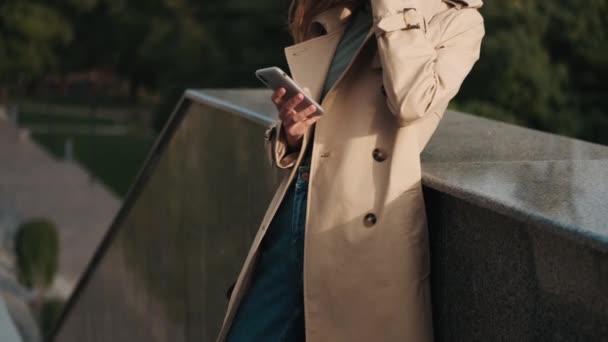 Conceptual Shot Stylowej Kobiety Ubranej Płaszcz Okopowy Przy Użyciu Smartfona — Wideo stockowe