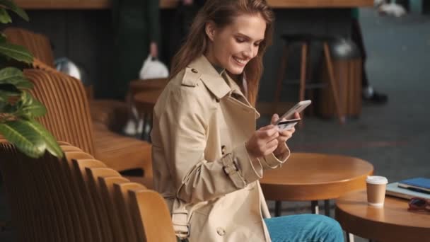 Pretty Uśmiechnięta Uczennica Ubrana Płaszcz Wygląda Inspirująco Płacąc Kartą Kredytową — Wideo stockowe