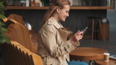 Kahve molasında kredi kartı ve akıllı telefon kullanarak kafede fatura ödeyen güzel bir öğrenci. Modern teknoloji