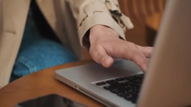 Güzel, mutlu öğrenci bir kafede oturuyor. İnternette kredi kartıyla ödeme yapmak için laptop kullanıyor. Modern teknoloji