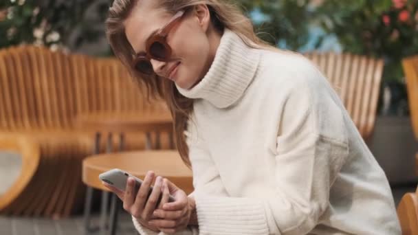 Bella Ragazza Sorridente Occhiali Sole Vestita Accogliente Maglione Bianco Cercando — Video Stock