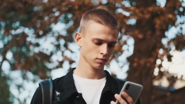 Akıllı telefondan sınıf programına bakan çekici erkek öğrencinin portresi.