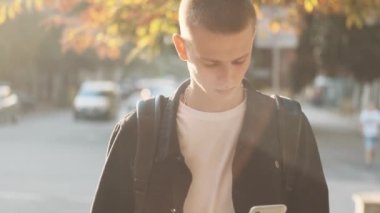 Çekici sıradan öğrenci arkadaşlarıyla mesajlaşıyor. Üniversiteye giderken akıllı telefon kullanıyor. Şehir sokaklarında.