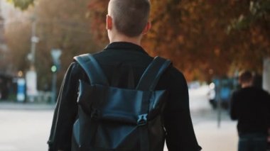 Üniversitede okuduktan sonra eve dönen sırt çantalı çekici öğrenci. Şehir caddesinde yürüyen genç bir öğrenci