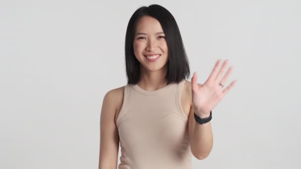 Όμορφη Ασιάτισσα Που Δείχνει Χαρούμενη Χαιρετώντας Ένα Φίλο Απομονωμένο Λευκό — Αρχείο Βίντεο
