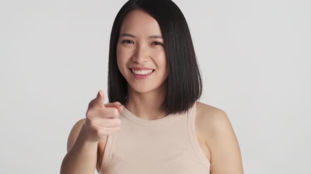 迷人的亚洲女孩用食指在白色背景下高兴地直勾勾镜头 — 图库视频影像