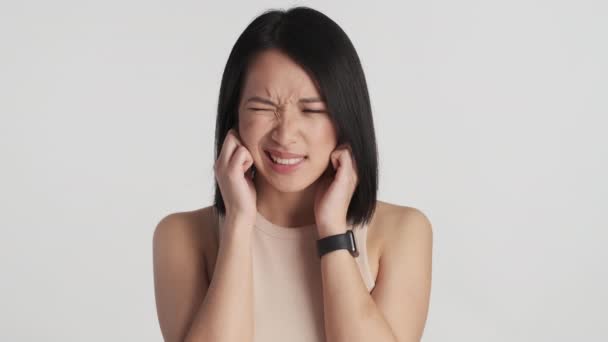 年轻的亚洲女人用手指捂住耳朵 远离白色背景的噪音 这么大声的表达 什么都不想听 — 图库视频影像