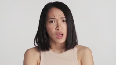 Genç üzgün Asyalı kadın beyaz arka planda suçlu görünüyor. Üzücü ifade