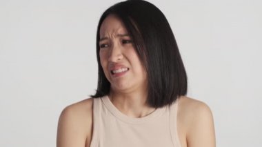 Genç Asyalı kadın, beyaz arka plan üzerinden kameraya bakmaktan rahatsız oluyor. İfadeyi sevmiyorum.