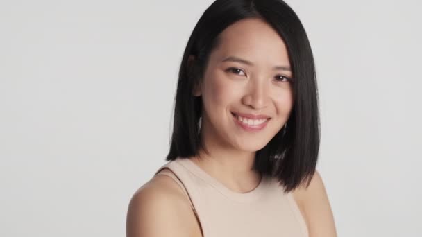 Ganska Positiv Asiatisk Flicka Ser Glad Och Ler Över Vit — Stockvideo
