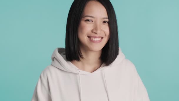 Beyaz Kapüşonlu Güzel Asyalı Kız Renkli Arka Planda Mutlu Görünüyor — Stok video
