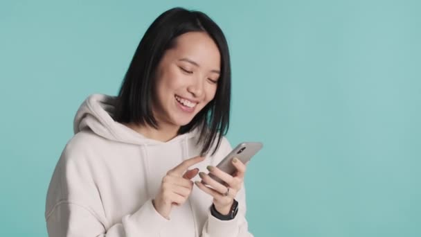 Beyaz Kapüşonlu Giyinmiş Neşeli Asyalı Kız Mutlu Görünüyor Mavi Arka — Stok video