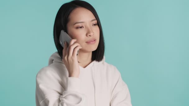 후드를 배경으로 스마트폰으로 대화하는 아름다운 아시아 떨어져 의사소통 — 비디오