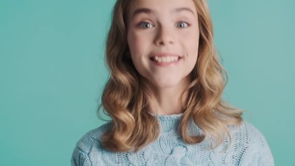迷人的金发少女 一头卷曲的秀发 在蓝色背景的相机上欢快地同意了 快乐的情绪 — 图库视频影像