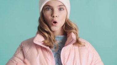 Pembe ceketli ve şapkalı genç kız renkli arka planda hava öpücüğü yolluyor.