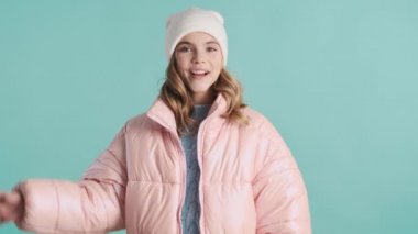 Pembe ceketli güzel sarışın genç kız ve mavi arka planda şapka takan arkadaş. Hoş kız el sallıyor