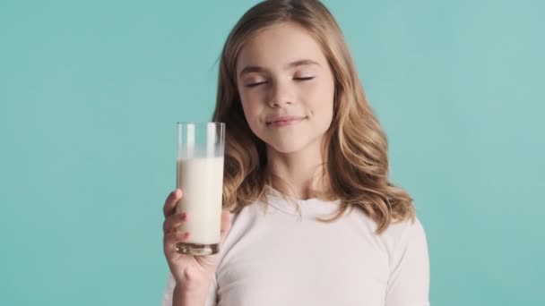 美丽的金发碧眼的少女 留着波浪般的头发 自信地摆出一副蓝底牛奶的架势 — 图库视频影像