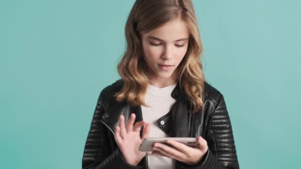 漂亮的金发少女在网上用蓝色背景的智能手机观看有趣的视频 — 图库视频影像