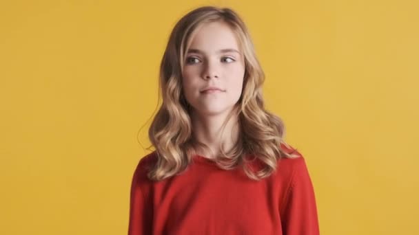 迷人的金发少女穿着红色毛衣 高兴地摇着头 在黄色背景下拿着头发在镜头前玩耍 — 图库视频影像