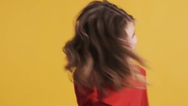 漂亮的金发少女 穿着红色毛衣 头上摇着头 在黄色背景的相机上玩毛绒玩具 快乐的情绪 — 图库视频影像