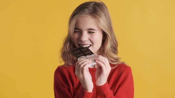 Приваблива Блондинка Дівчина Підліток Виглядає Щасливо Їсть Шоколад Жовтому Фоні — стокове відео