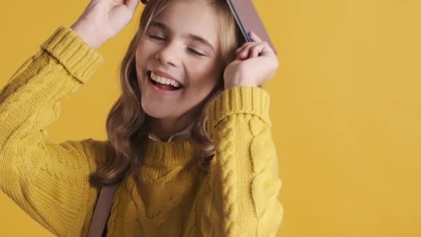 Ganska Blond Tonåring Student Flicka Poserar Med Bok Huvudet Ser — Stockvideo