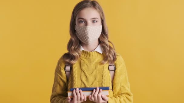 Atrakcyjna Blondynka Nastolatka Masce Ochronnej Stojąca Książkami Żółtym Tle Koncepcja — Wideo stockowe