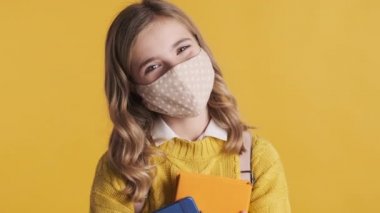 Sarı arka planda mutlu görünen koruyucu maske takan çekici sarışın genç kız. Güvenlik önce gelir.