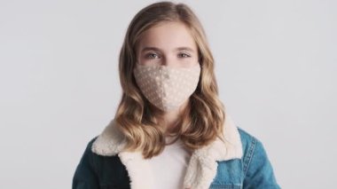 Koruyucu maske takan güzel sarışın kız sarı arka planda izole edilmiş koronavirüs salgınıyla kendini koruyor. Önce güvenlik kavramı