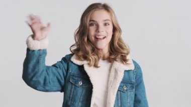 Güzel, sarışın genç kız el ele tutuşup kameraya sarıldı ve beyaz arka planda izole edilmiş arkadaşına el salladı. Gel bana, sana sarılmak istiyorum.