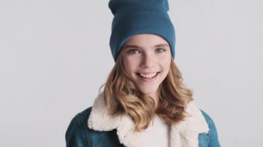 Beyaz arka planda barış jesti gösteren pozitif sarışın kız. Stüdyoda poz veren mutlu kız