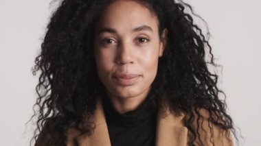 Genç, şehvetli, siyah saçlı Afrikalı Amerikalı kadın beyaz arka planda kameraya evet diyor. Kabul eden ifade