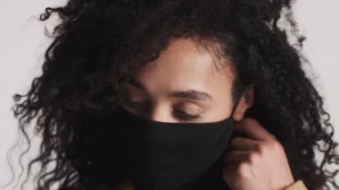 Beyaz arka planda mutlu görünen Afro-Amerikan kadın tıbbi maskesini çıkarıyor. Güvenlik kavramı