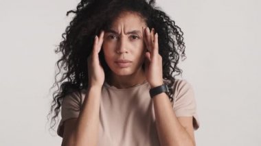 Koyu tüylü Afro-Amerikan kadın şakaklarına masaj yapıyor ve baş ağrısının beyaz arka planda izole olduğunu düşünüyor. Baş ağrısı.