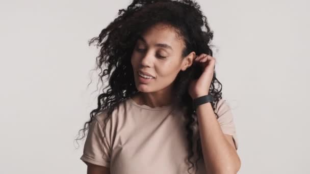 白い背景の上にカメラをかわいいポーズを見て暗いふわふわの髪を持つ若い美しいアフリカ系アメリカ人女性 スタジオでのアフロ女性 — ストック動画