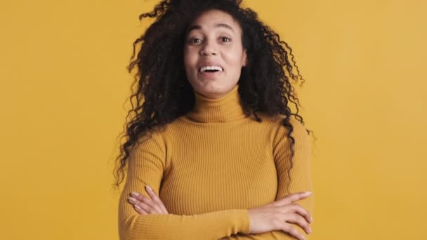 若い美しいアフリカ系アメリカ人の女性は 黄色の背景にカメラを笑いながら驚いている 肯定的な感情 — ストック動画