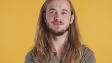 Sarı arka planda iyi haberler duyduğuna sevinen uzun saçlı, genç bir adam. Yüz ifadesi kavramı